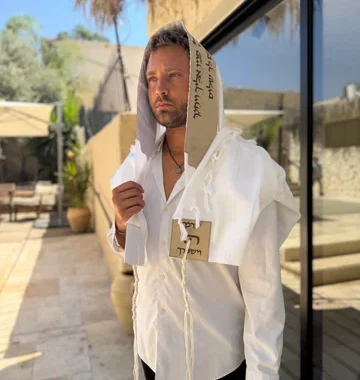 טלית מהודרת עם עיטורים מסורתיים מקופלת על גבי משטח עץ