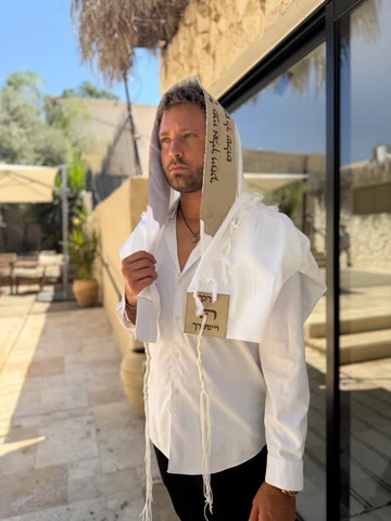 טלית מהודרת עם עיטורים מסורתיים מקופלת על גבי משטח עץ